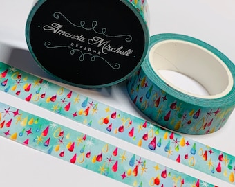 Può includere: Due rotoli di nastro washi con sfondo verde acqua e un motivo di gocce di pioggia colorate e stelle dorate. Il nastro è etichettato "Amanda Mischell Designs."