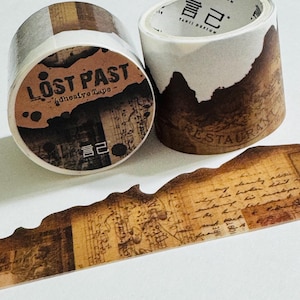 May include: Two rolls of adhesive tape featuring a vintage aesthetic with brown, sepia, and cream tones. The tape displays printed text including "LOST PAST" and "RESTAURANT," along with musical notation and handwritten script patterns.