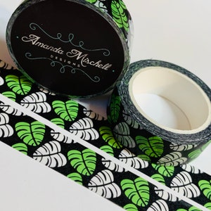 May include: Two rolls of washi tape with a black background and a green and white tropical leaf pattern. The tape is labeled "Amanda Mischell Designs".