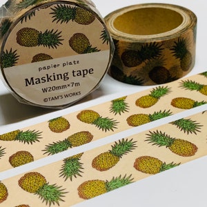 May include: Masking tape rolls with a repeating pattern of yellow and green pineapples on a tan background. The tape is labeled "papier platz Masking tape W20mm×7m ©TAM'S WORKS."