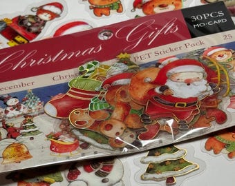 May include: A pack of Christmas-themed PET stickers featuring Santa Claus, reindeer, Christmas trees, and other festive designs. The sticker pack includes the text "Christmas Gifts" and "30 PCS MO-CARD". The stickers are colorful and have a glossy finish.