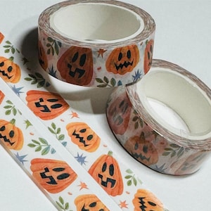 May include: Decorative washi tape rolls featuring orange jack-o'-lanterns with black facial features, green leaves, and blue star accents. The tape is designed for crafting and scrapbooking, perfect for Halloween-themed projects.