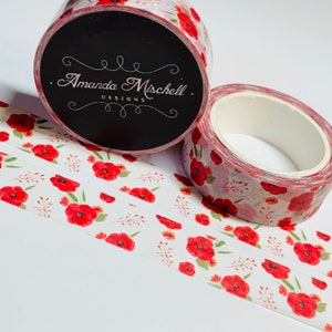 May include: Two rolls of washi tape with a floral pattern featuring red poppies and green leaves on a white background. The tape is labeled "Amanda Mischell Designs."