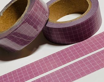Puede incluir: Dos rollos de cinta washi morada con patrón de cuadrícula y núcleo marrón. Debajo de los rollos se ven dos tiras de la misma cinta. La cinta es ideal para scrapbooking, diario y proyectos de manualidades.