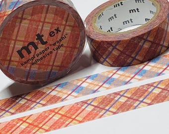 Puede incluir: Dos rollos de cinta adhesiva mt ex kamoi paper "washi" con un patrón de cuadros en tonos naranja, rojo, azul y morado. El texto "mt ex" y "kamoi paper 'washi' adhesive tape" es visible en un rollo. También se ven dos tiras de cinta.