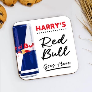 May include: Square coaster with a Red Bull can illustration. The coaster has the text "HARRY'S Red Bull Goes Here" in red and black. The Red Bull can is blue, white, and red.