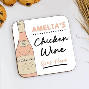 May include: A square coaster with the text "AMELIA'S Chicken Wine Goes Here." The coaster features a pink wine bottle illustration with the words "La Chicken Wine" and a rooster and hen graphic. The background is white.