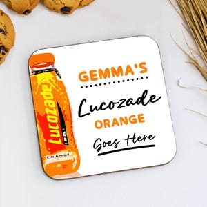 May include: Square white coaster featuring an orange and yellow Lucozade bottle design. The coaster has the text "GEMMA'S Lucozade ORANGE Goes Here" in orange and black. The coaster is on a white surface.