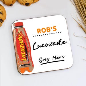 May include: Square white coaster featuring a Lucozade bottle illustration. The coaster has the text "ROB'S", "Lucozade", and "Goes Here" in black and orange. The coaster is on a white surface.