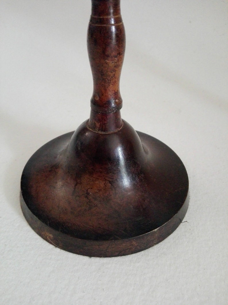 May include: A dark brown wooden candlestick with a bell-shaped base and a turned wooden stem.