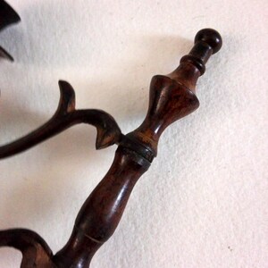 May include: A close-up of a wooden pipe with a dark brown finish. The pipe has a decorative design and a round mouthpiece.