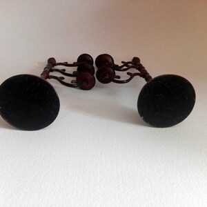 May include: A set of two black metal candle holders with a wooden base and four candle cups. The candle holders have a decorative design and are perfect for adding a touch of elegance to any room.