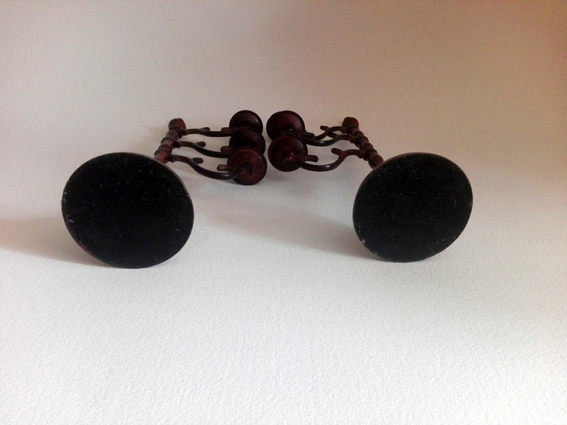 May include: A set of two black metal candle holders with a wooden base and four candle cups. The candle holders have a decorative design and are perfect for adding a touch of elegance to any room.