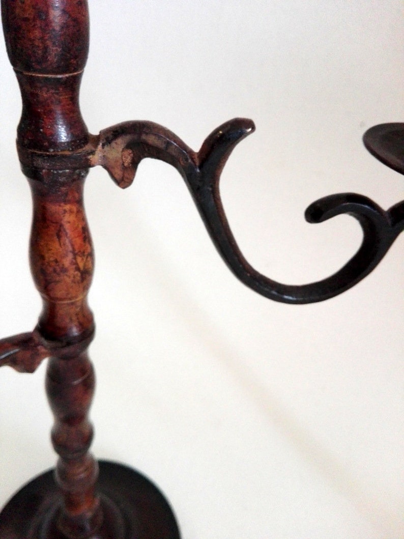May include: A wooden candle holder with three black metal candle arms. The candle holder has a dark brown finish and a round base.