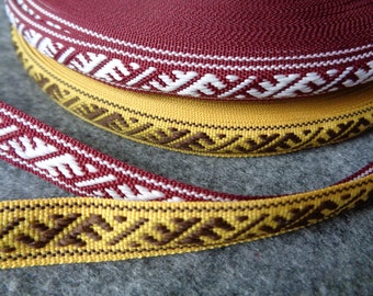 May include: Two rolls of decorative trim with geometric patterns. The trim is woven with maroon, white, yellow, and brown threads.