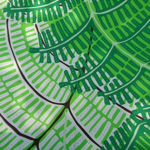 May include: A close-up of a fabric with a repeating pattern of green and white fern-like shapes on a bright green background. The design features detailed leaf structures with brown stems, creating a natural, botanical theme.