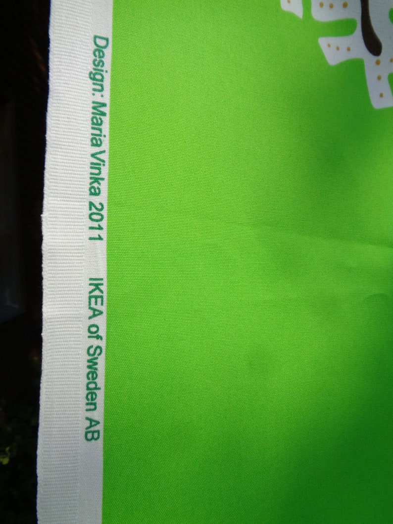 May include: Vibrant green fabric with a white border. The border displays the text "Design: Maria Vinka 2011" and "IKEA of Sweden AB" in green. The fabric has a textured finish.