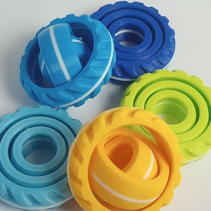 May include: Five colorful interlocking rings made of plastic. The rings are blue, green, yellow, and white. The rings are designed to be stacked and interlocked.