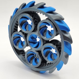 May include: A 3D-printed wheel with a complex design, featuring a series of circular openings and a surrounding ring. The wheel's outer edge has alternating blue and gray blades. The wheel's design is intricate and appears to be a mechanical component.