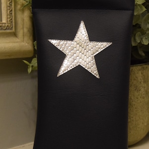 May include: A black leather glasses case with a silver star design.