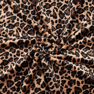 Könnte beinhalten: Ein weicher Stoff mit einem sich wiederholenden Leopardenmuster in Braun-, Beige- und Schwarztönen. Das Material ist in der Mitte gerafft, wodurch ein Spiraleffekt entsteht, der die Textur und das dichte Tierfellmuster hervorhebt.