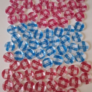 Può includere: Una collezione di bottoni rotondi con motivi a quadri rossi, bianchi e blu. I bottoni sono disposti in modo sparso, con un mix di design a quadri rossi e bianchi, blu e bianchi e rosa e bianchi. Ogni bottone ha quattro fori.