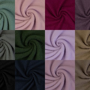 Peut inclure: Une grille de vingt-trois échantillons de tissu en polaire douce et texturée. Chaque carré présente une couleur unie différente, incluant des nuances de beige, gris, vert, rose, violet, marron, bleu, noir et rouge foncé, toutes en spirale.