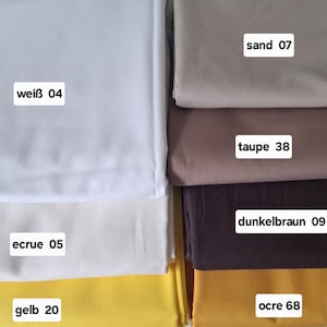 Könnte beinhalten: Gefaltete Stoffmuster in verschiedenen Farben: Weiß, Ecru, Gelb, Sand, Taupe, Dunkelbraun und Ocker. Jedes Muster hat ein Etikett mit Farbnamen und -nummer.