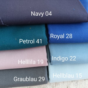 May include: A stack of fabric swatches in various shades of blue, green, and purple. The swatches are labeled with names and numbers, including Navy 04, Royal 28, Indigo 22, Hellblau 15, Graublau 29, Helllila 19, and Petrol 41.