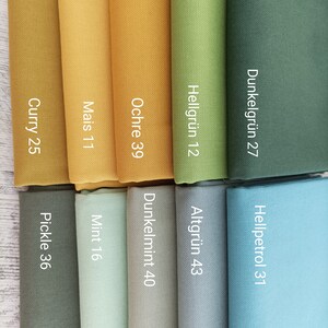 May include: Fabric swatches in various shades of green, blue, and yellow. The swatches are labeled with names and numbers, such as "Curry 25", "Mais 11", "Ochre 39", "Hellgr&uuml;n 12", "Dunkelgr&uuml;n 27", "Hellpetrol 31", "Altgr&uuml;n 43", "Dunkelmint 40", "Mint 16", and "Pickle 36".