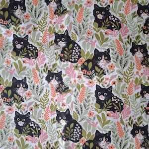 Peut inclure: Un tissu blanc avec un motif répétitif de chats noirs et blancs entremêlés d'éléments botaniques, notamment des feuilles vertes, des brins roses et de petites fleurs orange. Les chats ont des yeux jaunes et sont assis parmi le feuillage.