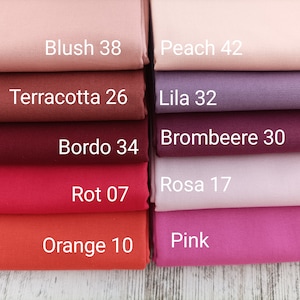 May include: A collection of fabric swatches in various colors, including blush, peach, terracotta, lila, brombeere, bordo, rosa, rot, orange, and pink. Each swatch has a color name and a number printed on it.