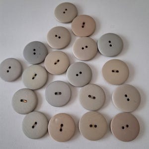 70 plastknappar, 2-håls, diameter 24 mm, i grått/beige.