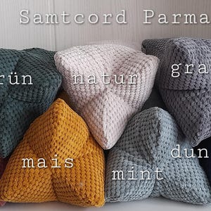 Puede incluir: Una colección de cojines triangulares de pana en varios colores, incluyendo verde oscuro, natural, gris, malva, maíz, menta y azul oscuro. Los cojines están apilados, con el texto "Samtcord Parma" y los nombres de los colores.