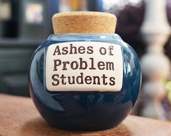 May include: A blue ceramic jar with a cork lid. The jar has a white label that reads "Ashes of Problem Students".