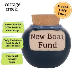 May include: A blue ceramic jar with a cork lid and a white label that reads "New Boat Fund". The jar is a great gift idea for someone saving up for a new boat.