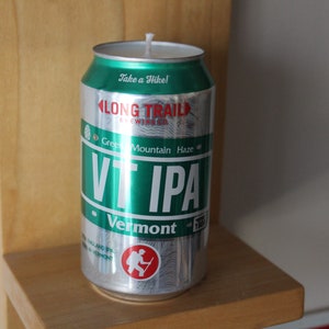 May include: A silver can candle shaped like a beer can. The can is green and has the words "Long Trail Brewing Co." and "VT IPA" on it. The can also has the words "Take a Hike!" and "Green Mountain Haze" on it.