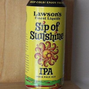May include: A yellow can of Lawson's Finest Liquids Sip of Sunshine IPA India Pale Ale. The can has a graphic of a stylized sun with a yellow center and orange rays.