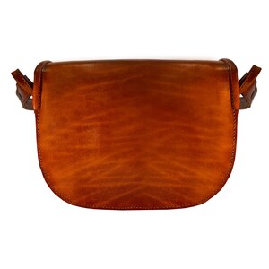 May include: A brown leather satchel bag with a flap closure and a strap. The bag is made of a soft, supple leather and has a vintage look.