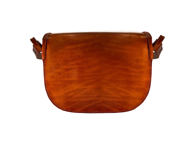 May include: A brown leather satchel bag with a flap closure and a strap. The bag is made of a soft, supple leather and has a vintage look.
