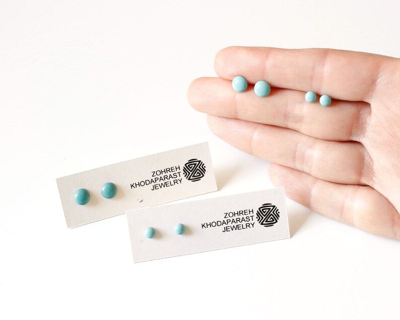 May include: Two pairs of turquoise blue stud earrings on white cards with the text "Zohreh Khodaparast Jewelry".