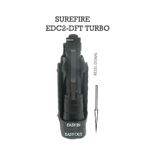 Puede incluir: Una linterna SureFire EDC2-DFT Turbo negra en una funda negra. La funda tiene el texto "Easy In Easy Out" impreso en ella. El texto "Bezel Down" está impreso en el lado derecho de la imagen.