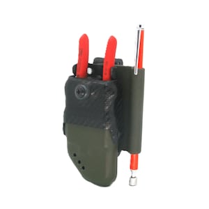 Könnte beinhalten: Ein dunkelgrüner Werkzeughalter mit schwarzem Oberteil, der zwei rotgriffige Werkzeuge und einen rot-silbernen Stift hält. Der Halter hat einen kleinen, runden Verschluss und drei kleine Löcher an der Seite. Die Werkzeuge sind teilweise sichtbar.