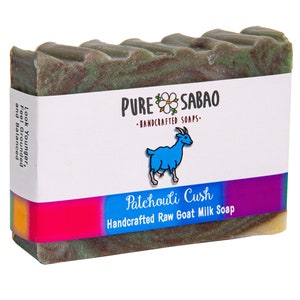 Puede incluir: Una pastilla de jabón artesanal de leche de cabra, de color verde y marrón, con una etiqueta que dice "PURE SABAO - JABONES ARTESANALES - Patchouli Cush Jabón artesanal de leche de cabra".