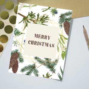 May include: A white card with a gold geometric frame and a botanical pattern of pine branches, berries, and leaves. The text "Merry Christmas" is printed in brown inside the frame.
