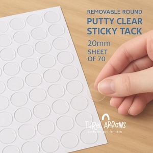 May include: A sheet of 70 clear, round, sticky tacks, each 20mm in diameter, with the text "REMOVABLE ROUND PUTTY CLEAR STICKY TACK". A hand holds one tack, showing its transparency. The brand name "THREE ARROWS" is also visible.
