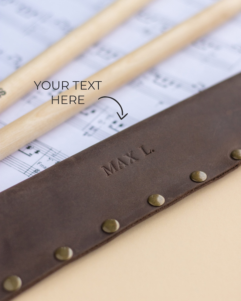 May include: Brown leather drumstick holder with brass rivets and the name "MAX L." embossed on the front.