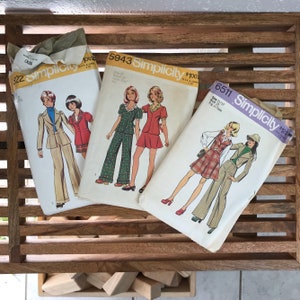 May include: Three vintage Simplicity sewing patterns for young women's clothing. The patterns are for sizes 11-12, 12, and 11/12. The patterns feature different styles of clothing, including a skirt and pants set, a dress, and a jumpsuit.