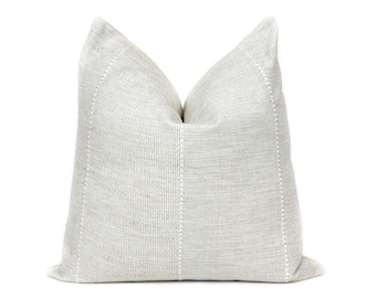 May include: A white throw pillow with a subtle woven texture and white stitching. The pillow is rectangular and has a slightly textured surface.