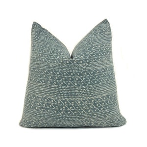 May include: A blue throw pillow with a white geometric pattern. The pillow is made of a soft, textured fabric.